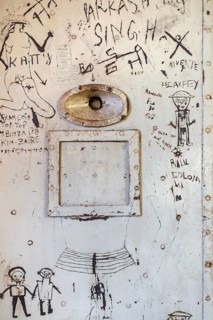 Graffiti on old steel jail cell door with spyhole and service-hatch at the prison museum at