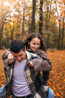 A happy family enjoys a playful moment in a vibrant autumn forest. Surrounded by colorful leaves,