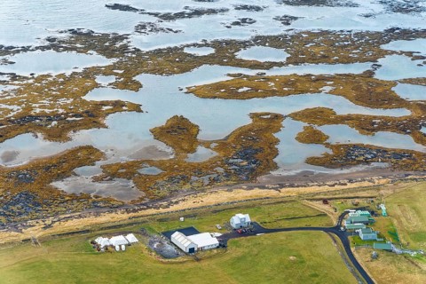 Aerial view of a small village in Iceland, near Reikiavik, featuring scattered houses and natural