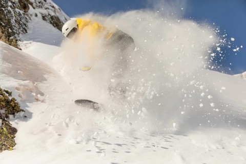 A skilled snowboarder carves through pristine powder on a sunny winter day in the mountains,