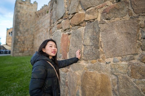 An Asian female tourist enjoys a memorable visit to Avila, Spain, exploring its impressive medieval