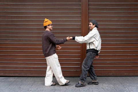 A Colombian couple enjoys a fun and carefree moment together outside, dancing against a modern