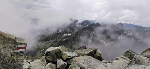 Mountains covered in fog with rugged rocks under cloudy sky, hiking trail, High Tatras, Slovakia