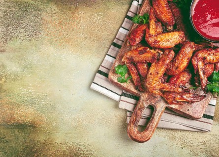 Fried in the oven, chicken wings, with spices, tomato sauce, on a cutting board, gray background,