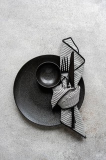 Elegant black and white table setting featuring a black plate, bowl, and cutlery with a striped