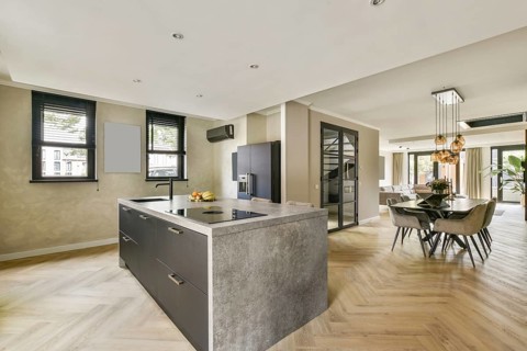 Stylish modern kitchen featuring an island countertop, elegant dining area, and light-colored walls