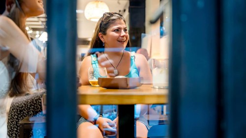 A woman enjoying dinner with friends in a cozy, warmly-lit restaurant. She is seated at a table