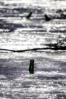 Discarded glass bottle in a frozen lake, winter, Germany