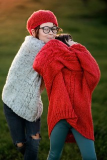 A young boy and girl embracing warmly during a sunset in autumn. Both are wearing knitted sweaters