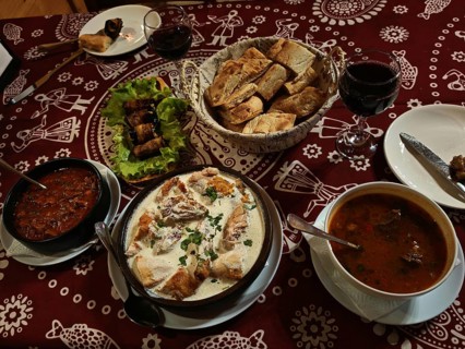 Table set with traditional food, bread, red wine and richly decorated tablecloth, Georgia