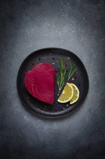 Fresh red tuna fillet, for steak, raw, top view, on a black plate, no people
