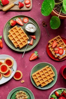Rustic waffles served with fresh strawberries and yoghurt on colorful plates. A romantic, homemade