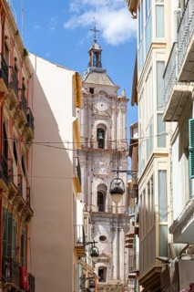Narrow alley with a view of an old church tower under a clear sky, Malaga, Spain