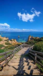 Wooden staircase leads to breathtaking views of rock arches, coastal cliffs and the sea, Praia do