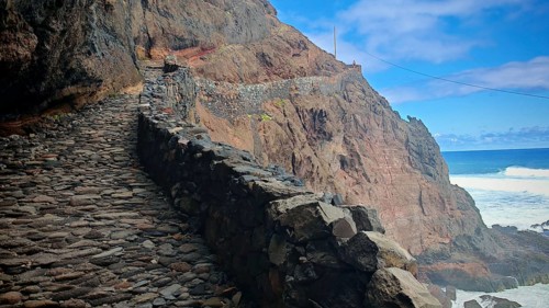 Stone trail bordered by rocks, volcanic stone hiking trail that winds along dramatic cliffs and the