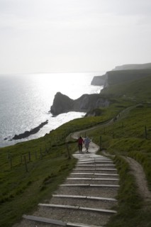 Couple walk up steps from Durdle Door, Jurrassic coast, Dorset, England, United Kingdom