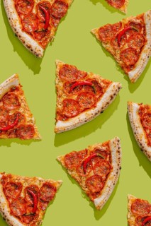 Top view of a pizza sliced into pieces, topped with tomato sauce, pepperoni, mozzarella cheese, hot