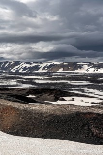 Snow-covered volcanic landscape with volcanic sand and petrified lava, crater of Askja volcano,
