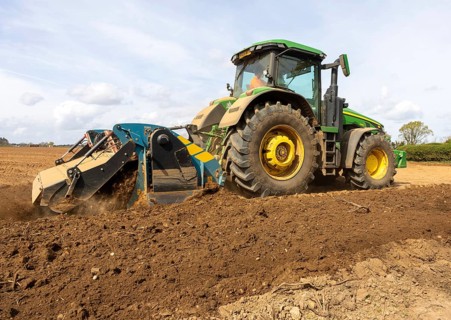 John Deere 8R 340 tractor engaged in field work operating an Agri-World FTC series soil tiller,