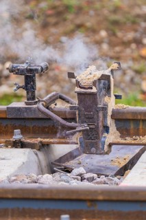 Detailed view of a metal device on the tracks with smoke development, rail welding, track