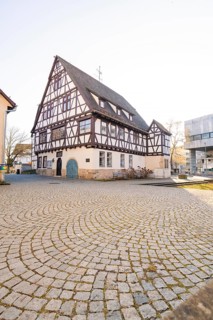 Large half-timbered house on a cobbled square under a clear sky, Sindelfingen, Böblingen district,
