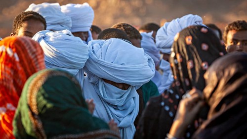 People wearing turbans and colourful clothing gather in the desert, the traditional Tuareg at the