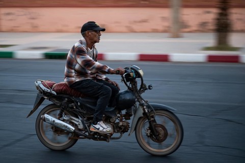 Marrakesh, MOROCCO - OCTOBER 5, 2024: Moroccan man riding a scooter on the road. Blurred background