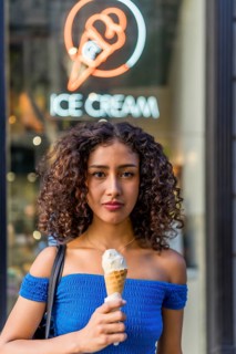 Vertical portrait of a beauty young latin woman in summer blue clothes holding ice cream outside