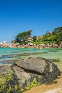 Beach with rocks and sand at the Plage Saint Guirec, with clear blue sky and colors as in the