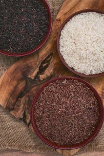 Set of red and black and white rice, in a bowl, on a wooden surface, rustic style, top view