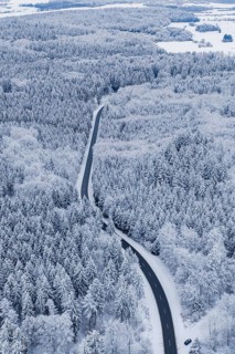 Snowy road snakes through a thick winter forest, Gechingen, Calw district, Germany
