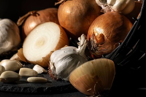 Onions and garlic in a basket in warm light on a dark background