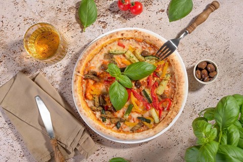 Closeup of a vegetarian pizza topped with vibrant zucchini, eggplant, peppers, and olives,