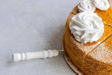 Top view of a delightful homemade honey cake topped with a creamy sour cream sauce, beautifully