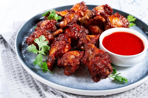 Crispy pieces of fried chicken, on a plate with sauce and herbs, in a modern kitchen environment,