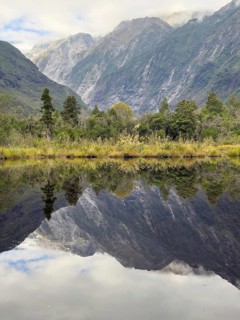 Hiking trail of the Roberts Point Track at Franz Josef Glacier with reflections of mountains in the