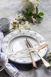 A beautifully arranged table setting featuring a vintage plate, cutlery with a thank you tag, and