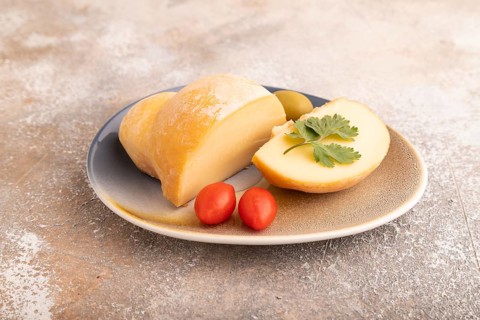 Smoked Mozzarella cheese, with tomatoes and olives on brown concrete background, side view, close