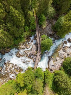Narrow wooden bridge over a wild river in a wooded area, Zillertal, Austria, Germany