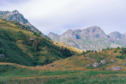 Scenic view of the lush green slopes and rocky peaks of the Ibones de Anayet in Huesca, Spain. The