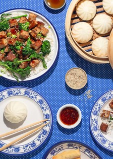 Top view of a traditional Chinese meal featuring steamed buns, tofu, and spring rolls on a blue