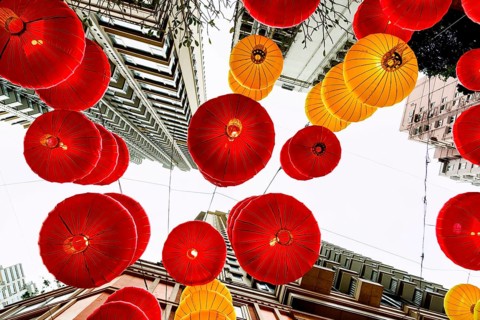 From below view of striking red and yellow lanterns adorning the cityscape of Hong Kong during the
