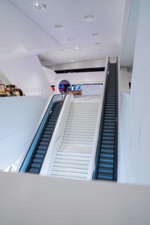 Modern escalator in a bright, futuristic exhibition hall, Porsche Museum, Stuttgart, Germany