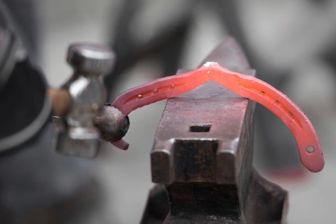 The blacksmith shakes the horseshoe on the anvil
