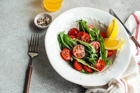 Fresh arugula and herb salad topped with juicy cherry tomatoes, seasoned with Himalayan salt,