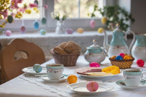 Decorated table with colorful easter eggs, pastries and cold platter