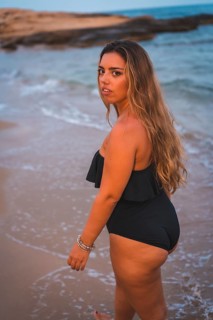 Lifestyle of a blonde Caucasian girl in a black swimsuit. Strolling on the seashore