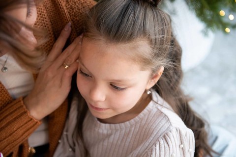 A touching scene captures a young girl looking down, nestled against her unrecognizable mother