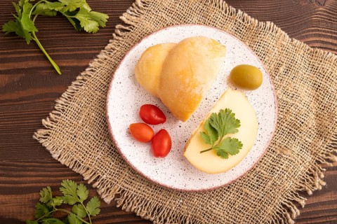 Smoked Mozzarella cheese, with tomatoes and olives on brown wooden background and linen textile,