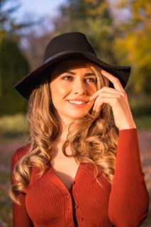 Lifestyle, portrait of a caucasian girl in a black hat at sunset in a green park